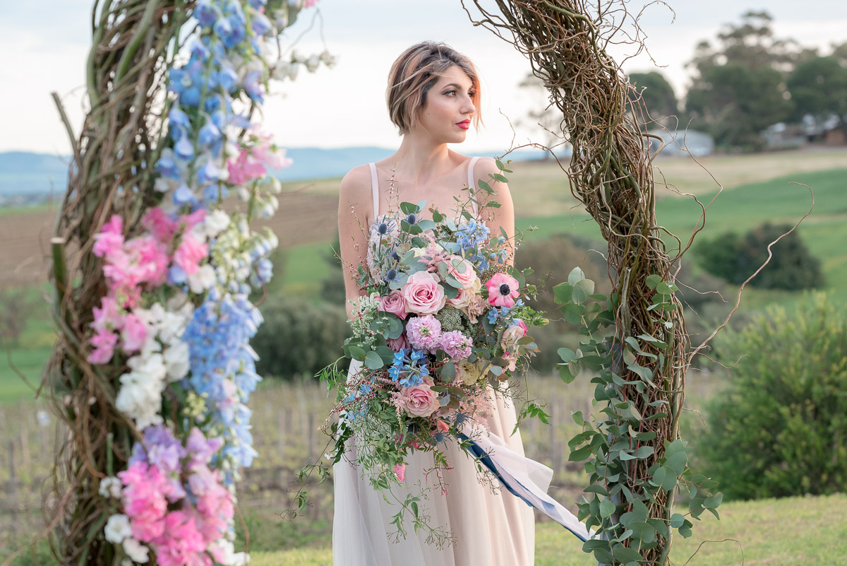 bride stands near arbour at same sex wedding