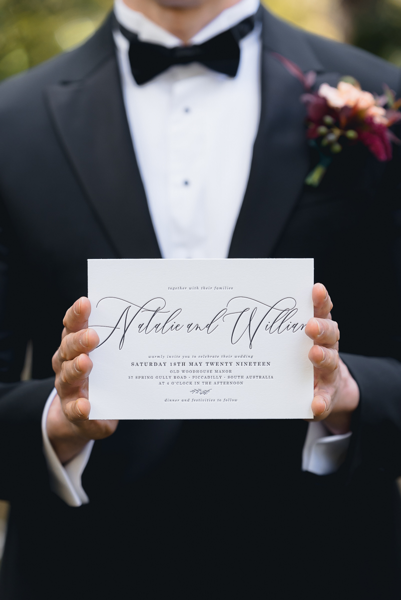 groom holding invitation to autumn wedding