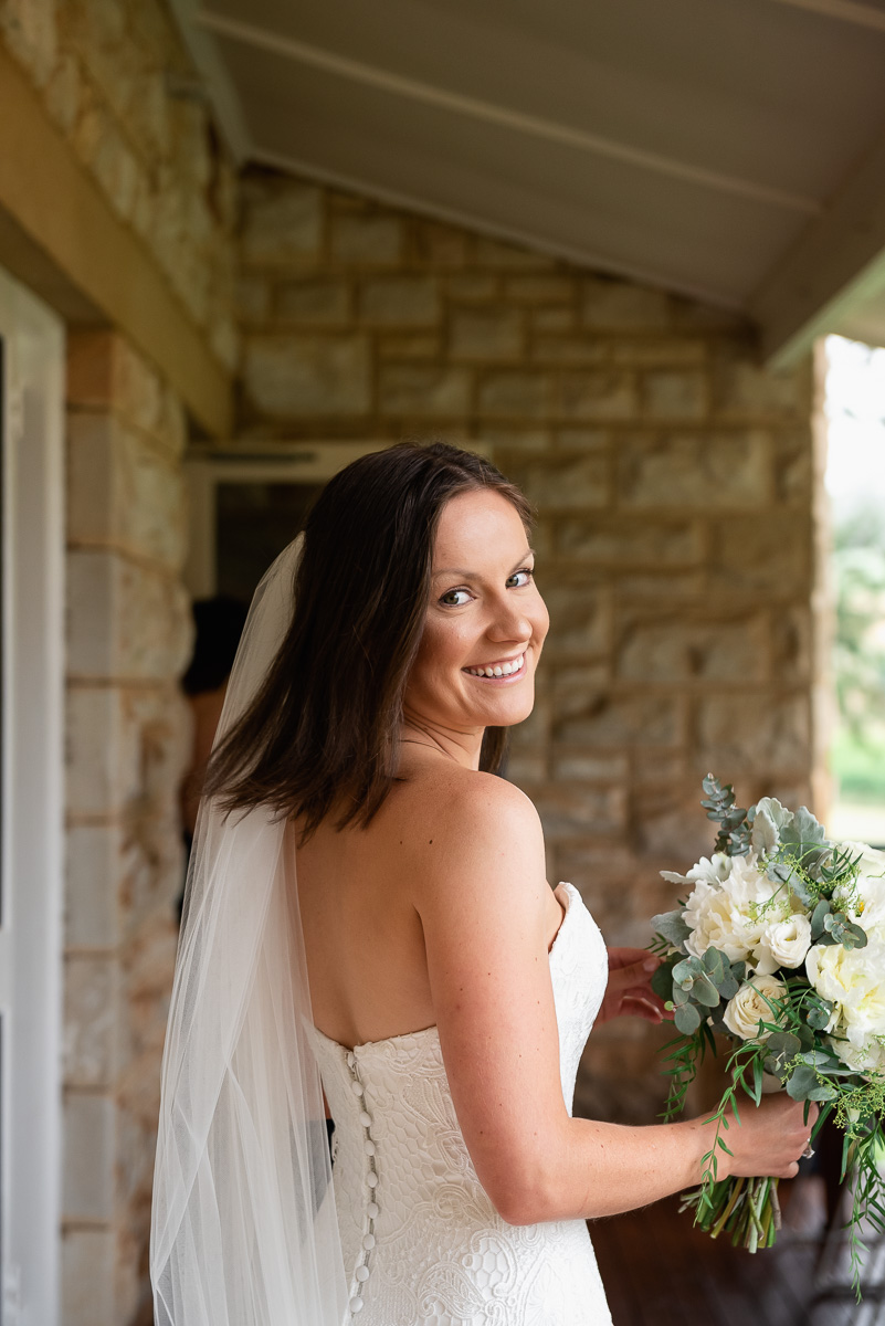 bride with bouquet looks at wedding photographer